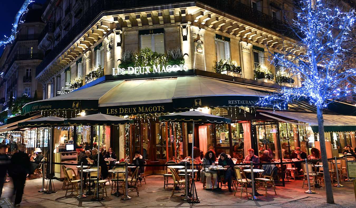 The outside of Le Deux Magots cafe, a cafe famous with writers and artists in the 1920s, lit up at night in Paris, France