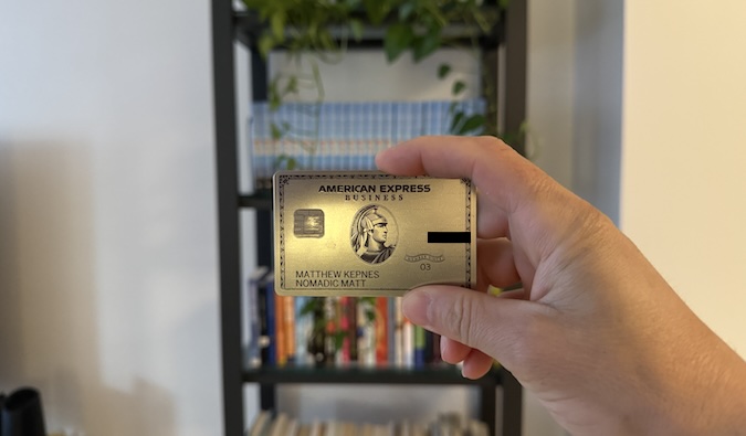 The American Express® Platinum Business Card Nomadic Matt being held up in front of a wall