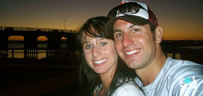 A traveling couple posing together in front of the sunset overseas