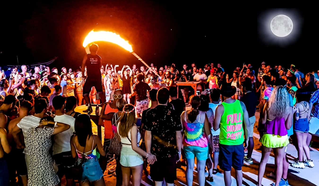A crowd of people watch fire throwers at a beach in Thailand during the Full Moon Party