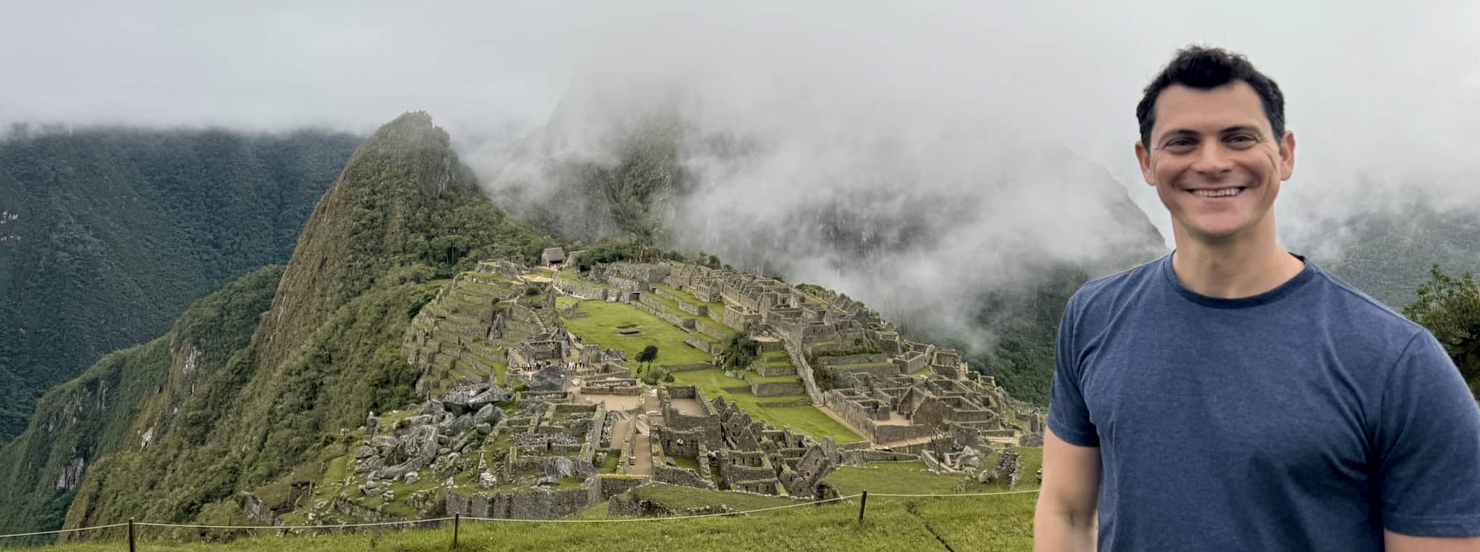Nomadic Matt posing near Machu Picchu in cloudy Peru