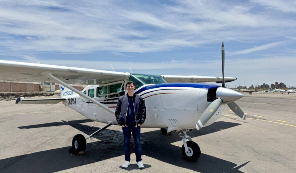 Nomadic Matt posing near a very small aircraft in Peru