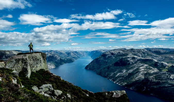 An adventurous traveler standing on a cliff looking over the landscape