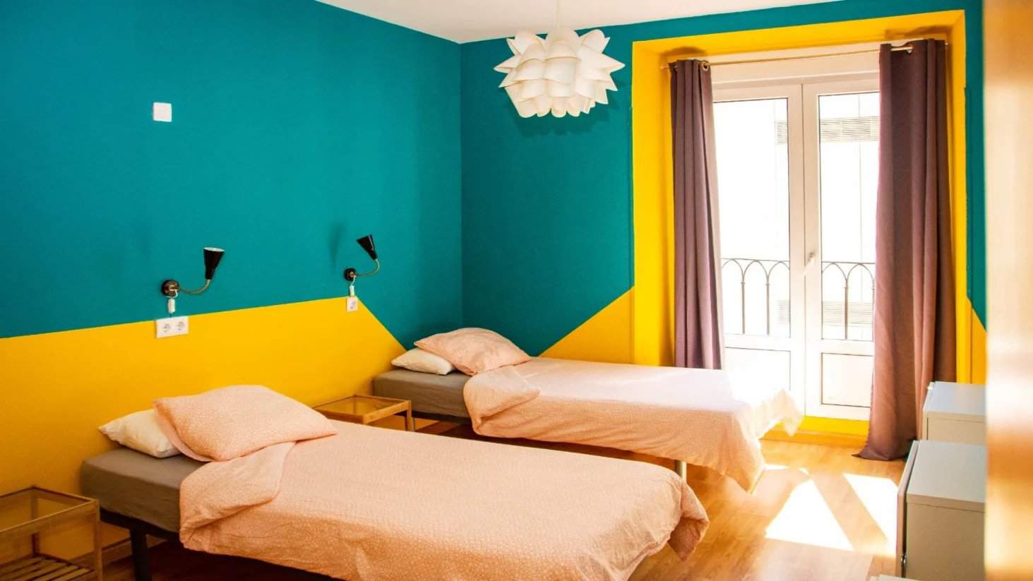 Two twin beds in a brightly painted room at Onefam Sungate hostel in Madrid, Spain.
